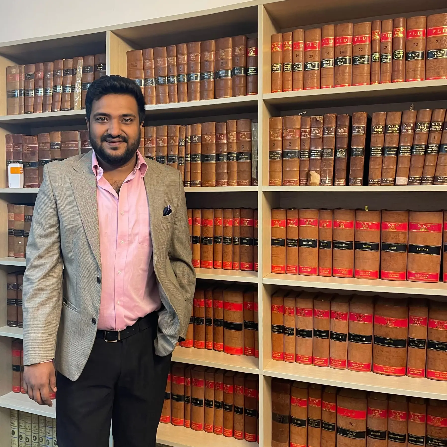 Cyrus standing beside shelves of legal books
